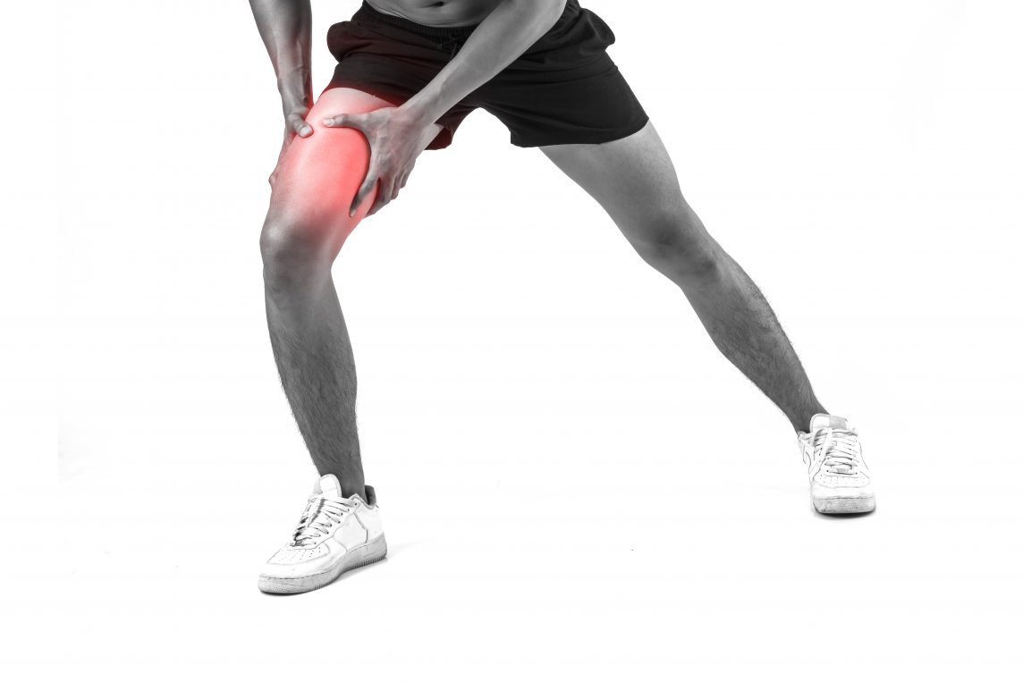 Young sport man with strong athletic legs holding knee with his